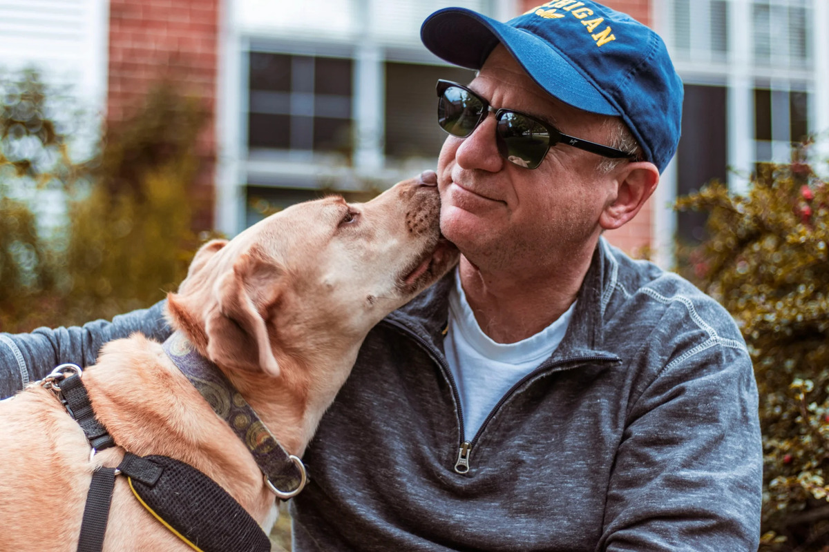 Middle-aged man in athletic wear sitting outdoors with his dog, representing active aging and mobility for longevity