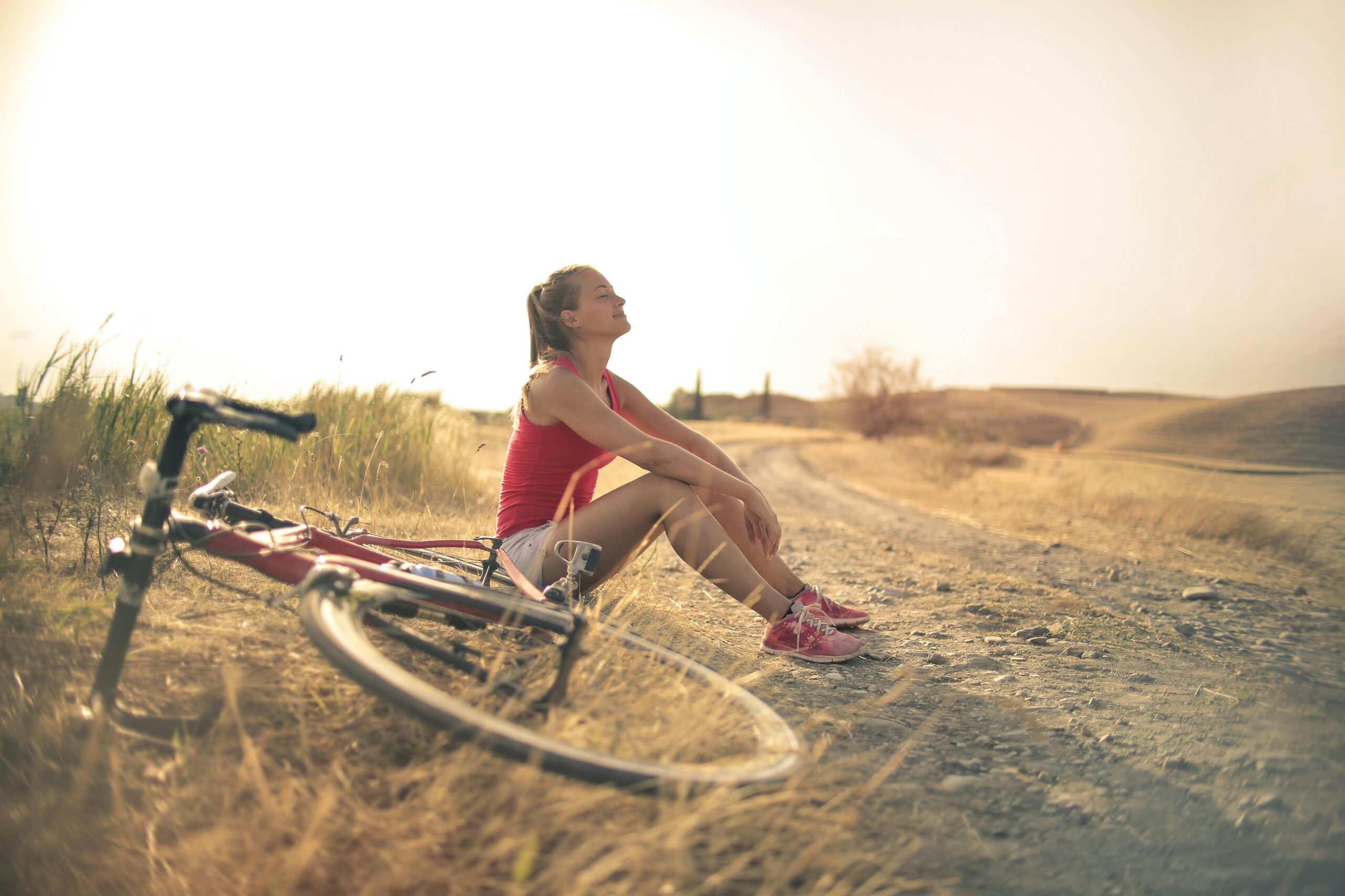 Woman experiencing everyday well-being by taking a peaceful breathing break beside her bicycle during golden hour
